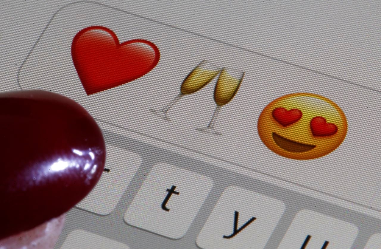 En esta ilustración fotográfica, un emoji o emoticón que representa un corazón, una copa de champán y ojos en forma de corazón se muestran en la pantalla de un iPhone