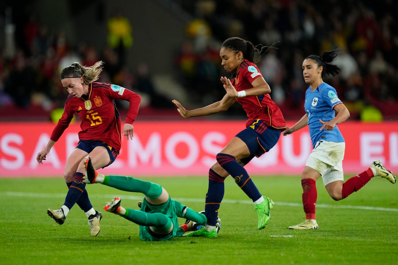 La portera francesa Pauline Peyraud-Magnin se zambulle para salvar frente a las españolas Salma Paralluelo y Eva Navarro, a la izquierda, durante el partido final de fútbol de la Liga Femenina de Naciones entre España y Francia en el estadio La Cartuja de Sevilla, España, el miércoles 28 de febrero de 2024. (Foto AP/José Bretón)