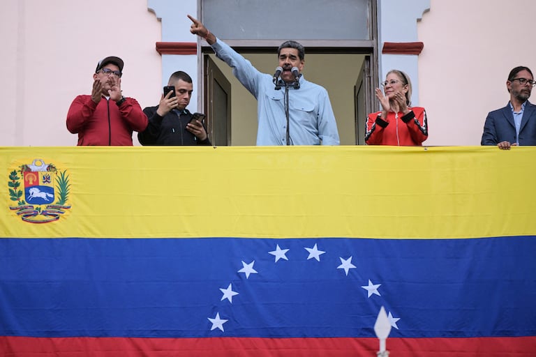 El presidente venezolano, Nicolás Maduro (C), acompañado por su esposa Cilia Flores (C-R), pronuncia un discurso ante sus seguidores durante una manifestación en el palacio presidencial de Miraflores en Caracas el 1 de agosto de 2024. El presidente de Venezuela, Nicolás Maduro, propuso este jueves "retomar" las negociaciones con Estados Unidos, país que no reconoció su reelección y apoya las acusaciones de fraude de la oposición. (Foto de Yuri CORTEZ / AFP)
