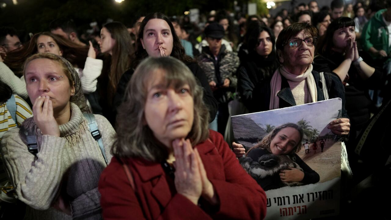 Familiares y amigos de personas asesinadas y secuestradas por Hamas y llevadas a Gaza, uno de ellos con una fotografía de Romi Gonen, reaccionan a la noticia durante una reunión en Tel Aviv, Israel, el domingo 19 de enero de 2025. (Foto AP/ Oded Balilty)