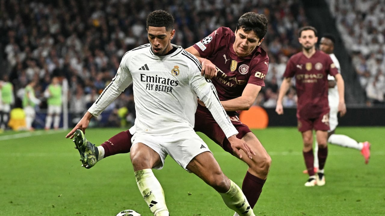El centrocampista inglés #05 del Real Madrid Jude Bellingham (izq.) es desafiado por el defensa uzbeko #45 del Manchester City Abdukodir Khusanov durante el partido de play-off de la fase eliminatoria de la UEFA Champions League entre el Real Madrid CF y el Manchester City.