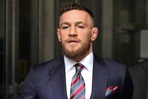 El luchador irlandés de artes marciales mixtas Conor McGregor (C) llega para hablar con la prensa después de declararse culpable de una sola violación de alteración del orden público.