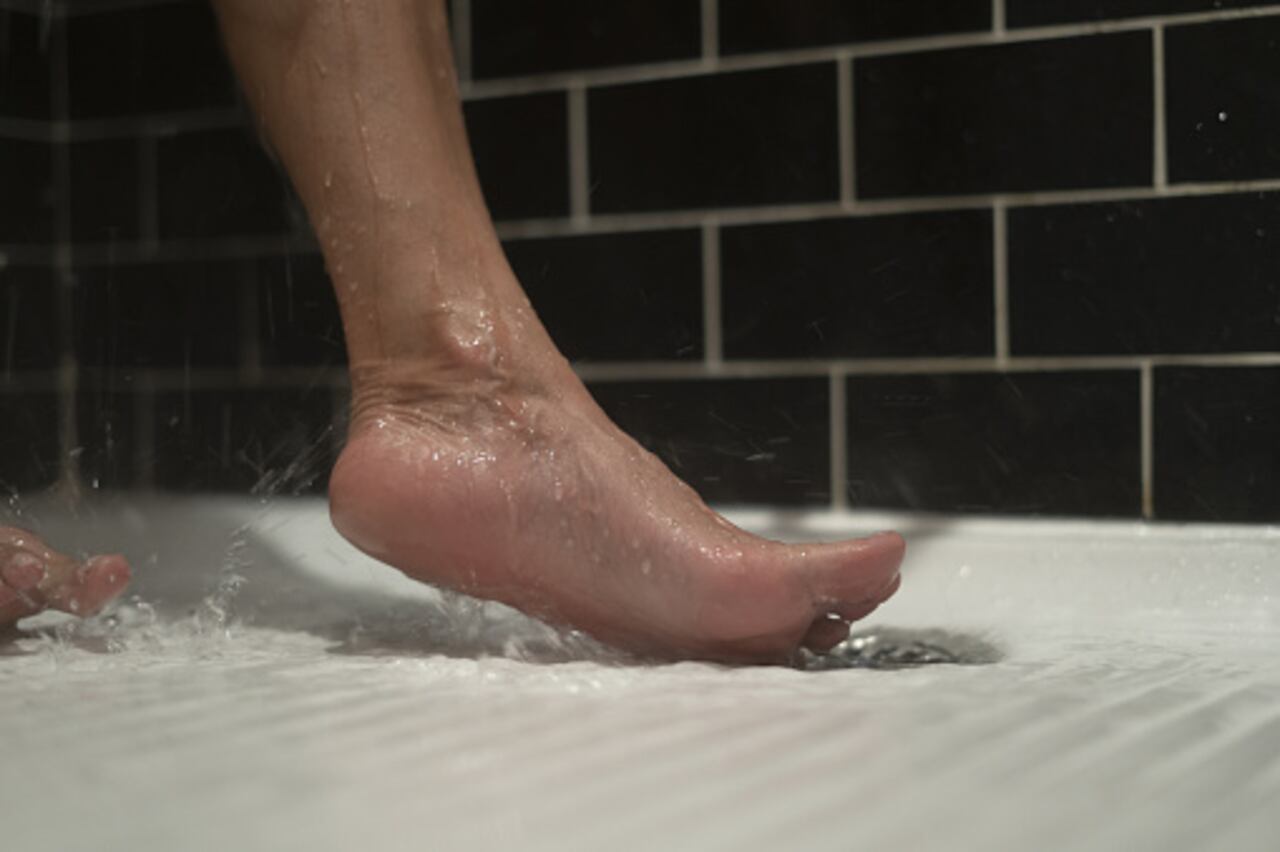 Shot of unidentified person's bare foot dripping water while in shower