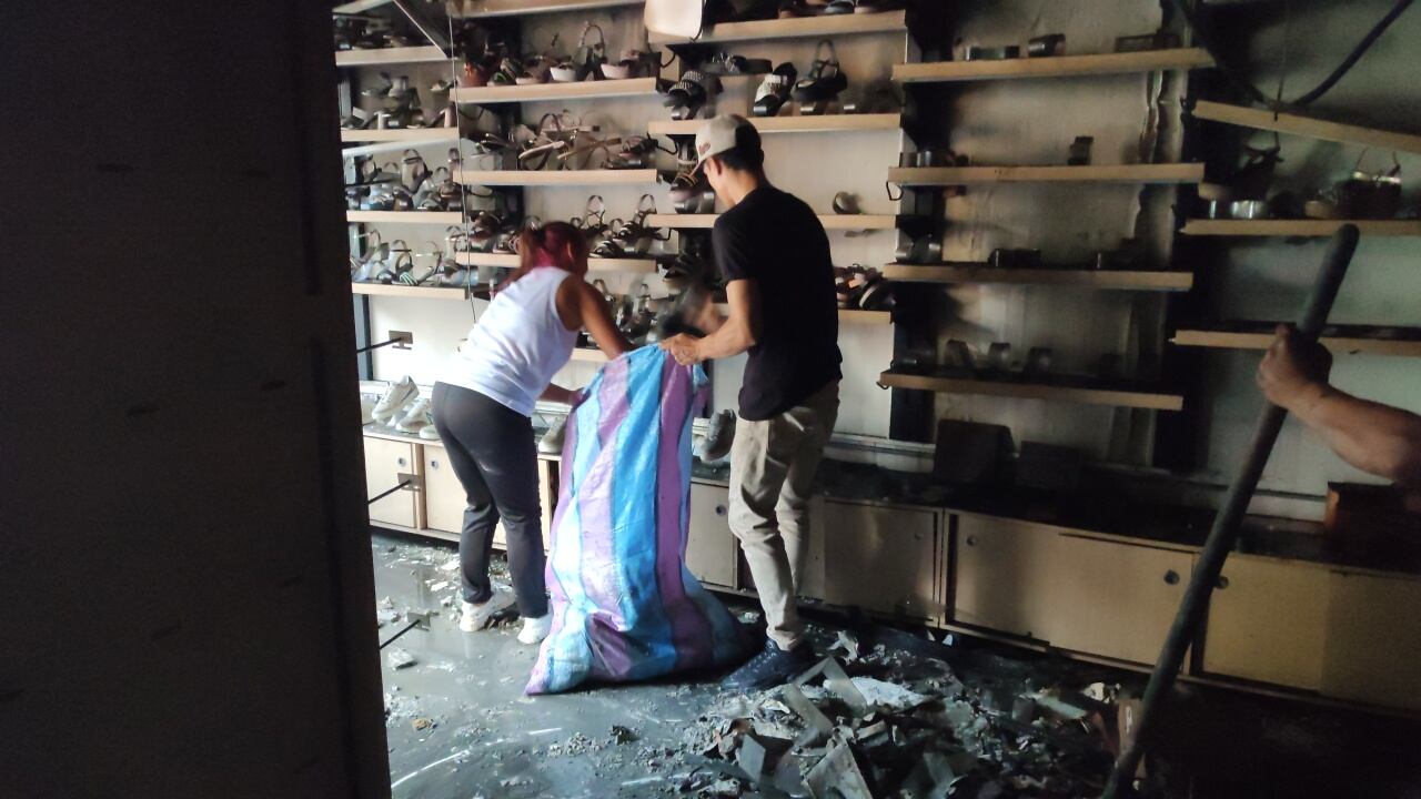 Comerciantes del centro de Cali rescatan lo que pueden del centro comercial el tesoro luego del incendio que consumió a este establecimiento.