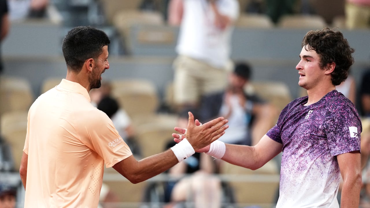 El ganador, el brasileño Joao Fonseca (derecha), saluda al serbio Novak Djokovic al finalizar su partido individual masculino en la sexta jornada del torneo de tenis Roland Garros, disputado en la pista Philippe-Chatrier del complejo Roland-Garros en París el 29 de mayo de 2026. (Foto de Dimitar DILKOFF / AFP)