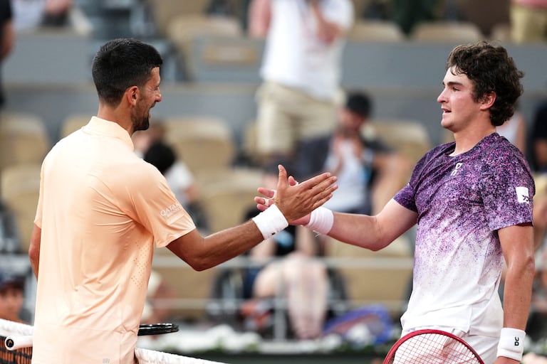 El ganador, el brasileño Joao Fonseca (derecha), saluda al serbio Novak Djokovic al finalizar su partido individual masculino en la sexta jornada del torneo de tenis Roland Garros, disputado en la pista Philippe-Chatrier del complejo Roland-Garros en París el 29 de mayo de 2026. (Foto de Dimitar DILKOFF / AFP)