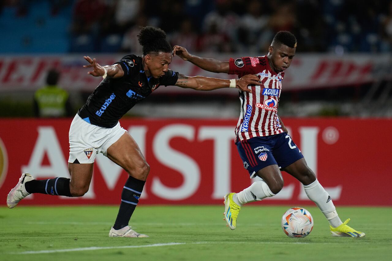 Deiber Caicedo del Junior de Colombia, derecha, y Ricardo Ade de la Liga Deportiva Universitaria de Ecuador, luchan por el balón durante un partido de fútbol del Grupo D de la Copa Libertadores en el Estadio Metropolitano