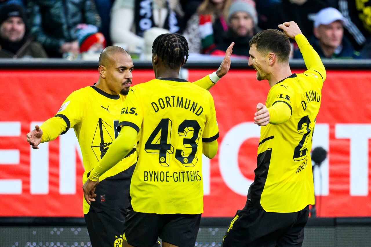 Donyell Malen, de Dortmund, a la izquierda, celebra el gol con sus compañeros Jamie Bynoe-Gittens y Thomas Meunier, a la derecha, durante el partido de fútbol de la Bundesliga entre el FC Augsburg y el Borussia Dortmund en el WWK-Arena, Augsburg, Alemania, el sábado 16 de diciembre de 2023. (Tom Weller /dpa vía AP)