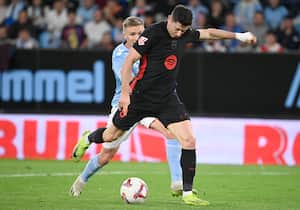 El delantero polaco del Barcelona #09 Robert Lewandowski anota el segundo gol de su equipo junto al defensor sueco del Celta de Vigo #02 Carl Starfelt durante el partido de fútbol de la liga española.