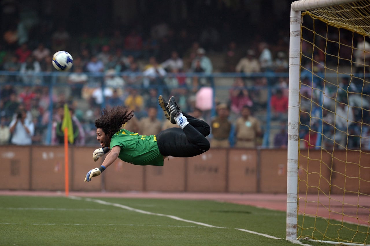 El ex portero colombiano René Higuita patea el balón para atajar un gol durante un partido de exhibición entre el Brazilian Masters y el Indian All Stars en Calcuta el 8 de diciembre de 2012. El equipo brasileño ganó el partido por 3-1. AFP PHOTO/ Dibyangshu SARKAR (Foto de DIBYANGSHU SARKAR / AFP)