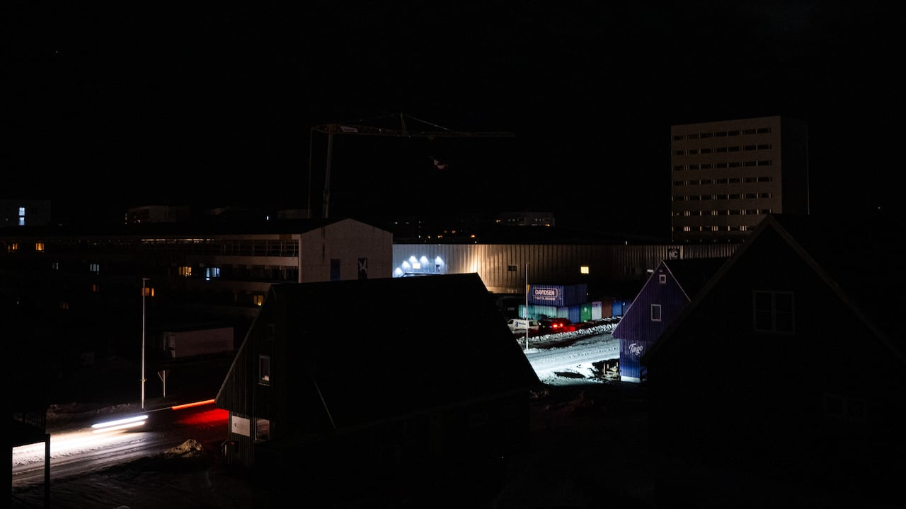 Una calle del centro de Nuuk se ilumina con los faros de un coche durante un apagón el 24 de enero de 2026 en Groenlandia. Un apagón dejó a oscuras la capital de Groenlandia durante el fin de semana, después de que fuertes vientos provocaran una falla en la transmisión, según informó la empresa estatal de servicios públicos.