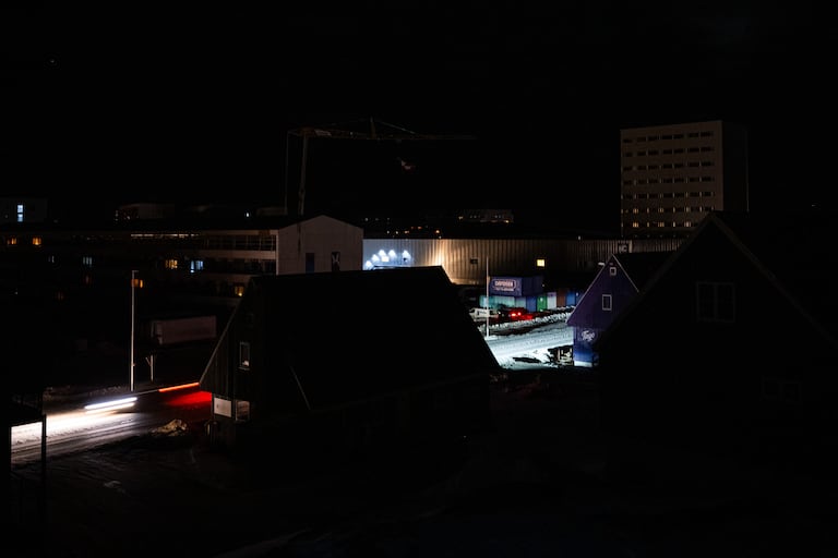 Una calle del centro de Nuuk se ilumina con los faros de un coche durante un apagón el 24 de enero de 2026 en Groenlandia. Un apagón dejó a oscuras la capital de Groenlandia durante el fin de semana, después de que fuertes vientos provocaran una falla en la transmisión, según informó la empresa estatal de servicios públicos.