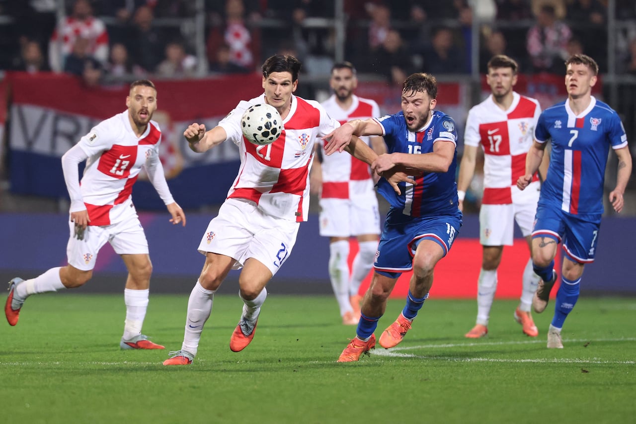 El delantero croata Igor Matanovic (nº 21, al frente a la izquierda) disputa el balón con el defensa feroés Gunnar Vatnhamar (nº 16) durante el partido de clasificación para la Copa Mundial de la FIFA 2026, correspondiente al grupo L de la zona europea, entre Croacia e Islas Feroe, en el estadio HNK de Rijeka, el 14 de noviembre de 2025. (Foto: AFP)