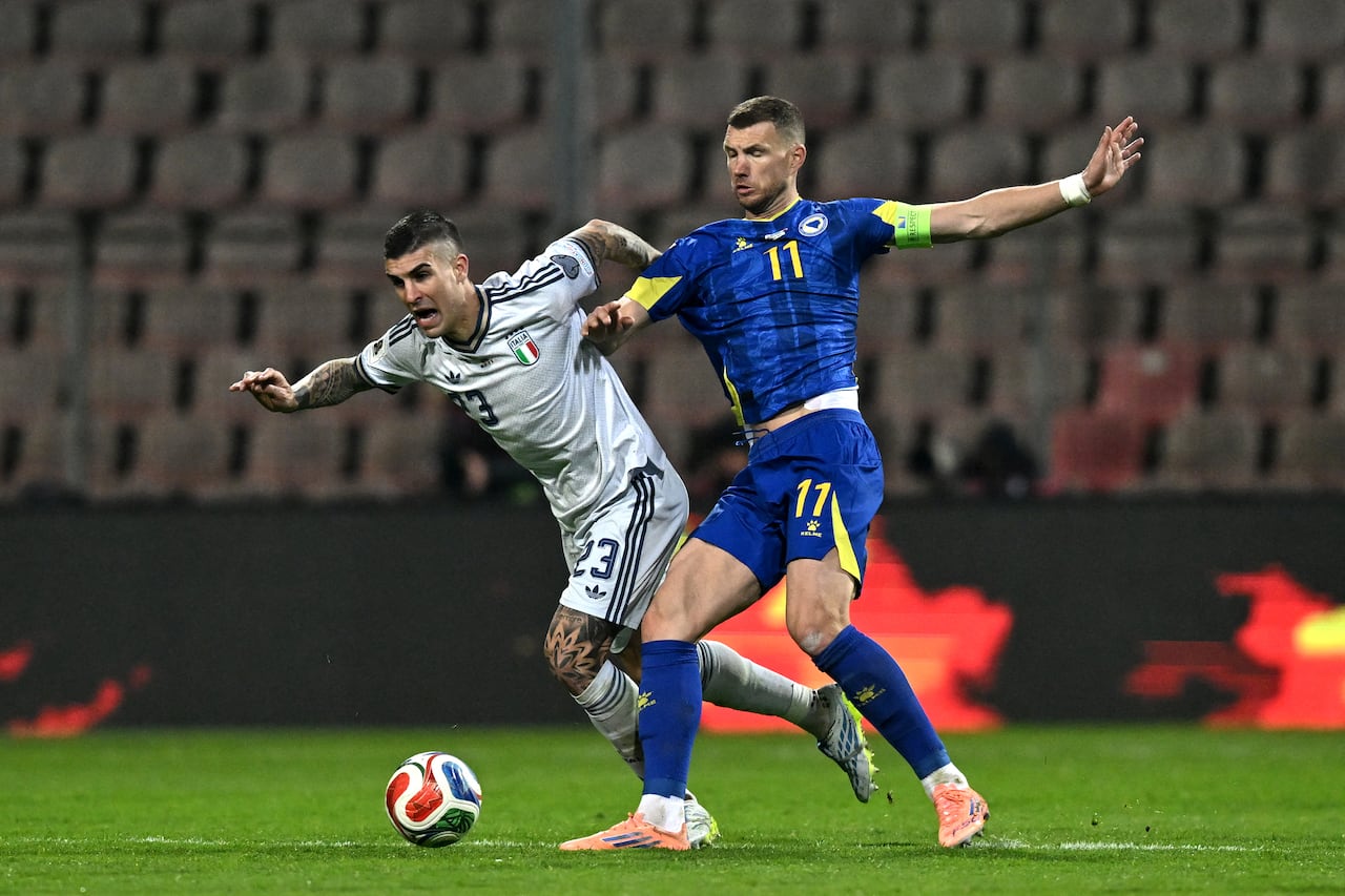 Edin Dzeko disputando un balón con un rival de Italia en el repechaje al Mundial 2026