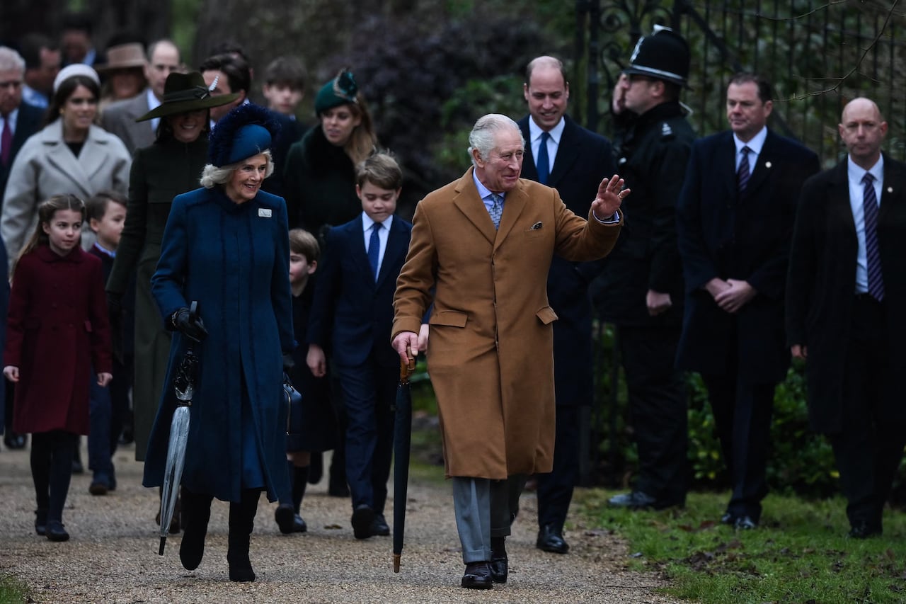 (FILES) Britain's King Charles III (R) flanked by Britain's Camilla, Queen Consort (L) waves to members of the public as he arrives for the Royal Family's traditional Christmas Day service at St Mary Magdalene Church in Sandringham, Norfolk, eastern England, on December 25, 2022. Britain's Charles III reaches the milestone of his first year as king this week, with his reign so far characterised by a smooth transition from that of his late mother, Queen Elizabeth II. (Photo by Daniel LEAL / AFP)