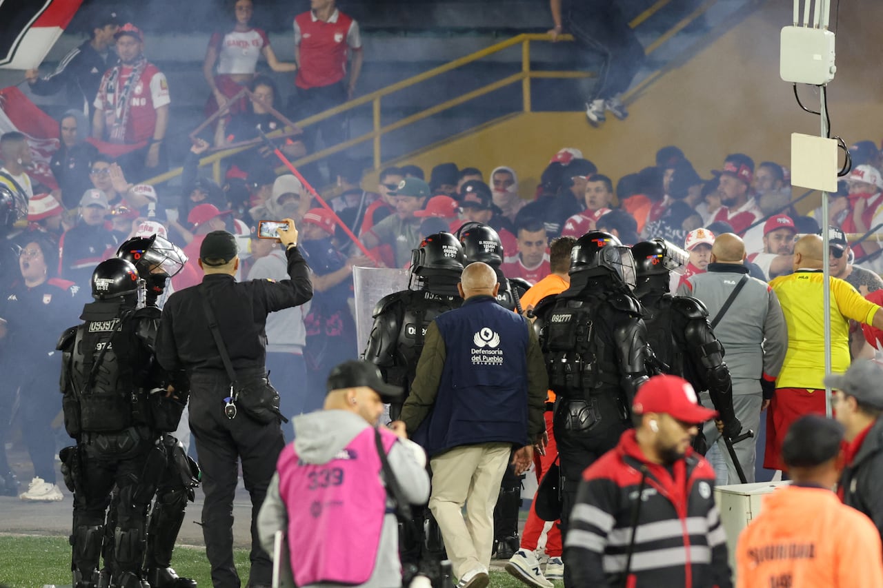 Fans of Santa Fe and America de Cali clash on the pitch during the Colombian league match between the two teams at the Nemesio Camacho El Campin Stadium in Bogota, Colombia, on August 22, 2026. (Photo by Daniel Garzon Herazo/NurPhoto) (Photo by Daniel Garzon Herazo / NurPhoto via AFP)
