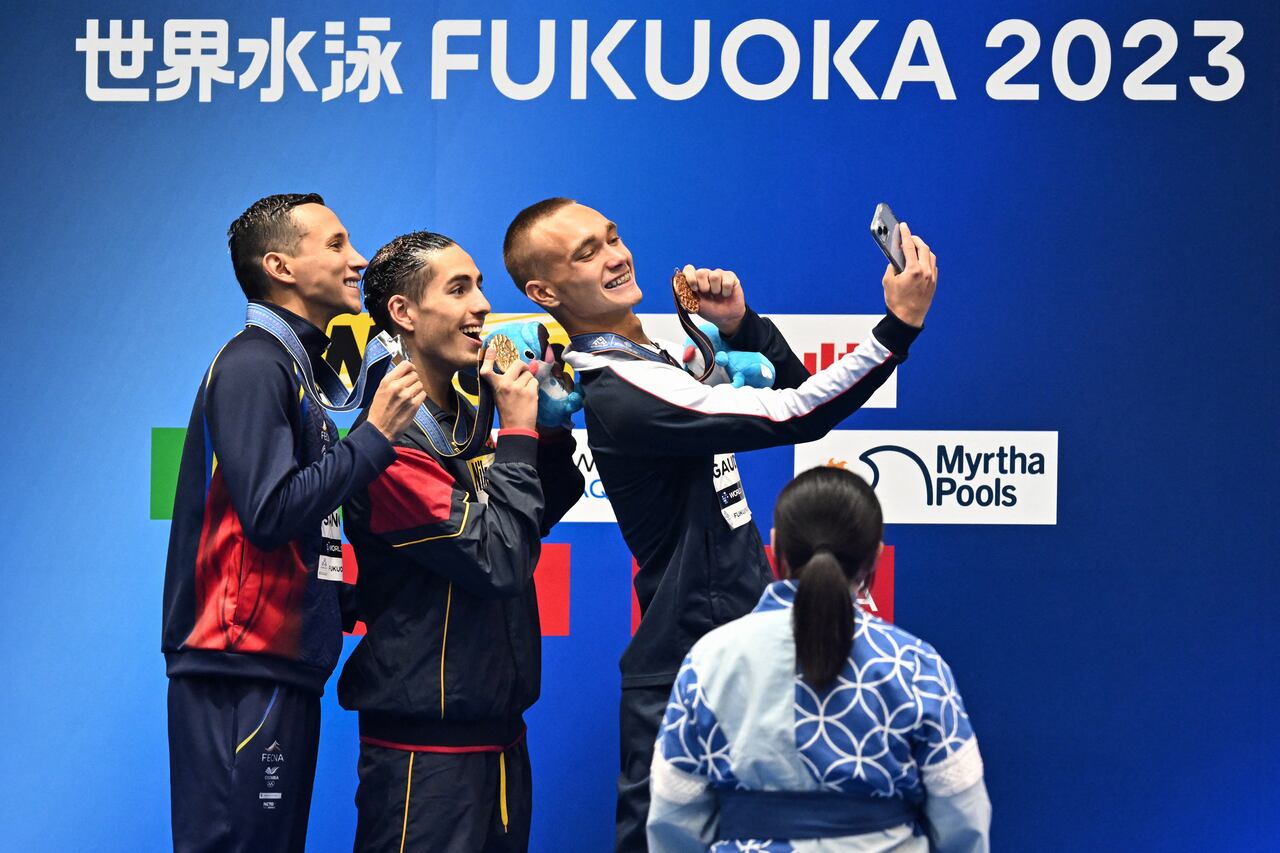 (De izquierda a derecha) Gustavo Sánchez, de Colombia, medallista de plata, Dennis González Boneu, de España, medallista de oro, y Kenneth Gaudet, de Estados Unidos, medallista de bronce, posan durante la ceremonia de entrega de medallas para el evento masculino de natación artística libre en solitario durante el Campeonato Mundial de Natación en Fukuoka el 19 de julio de 2023. (Foto de Philip FONG / AFP)