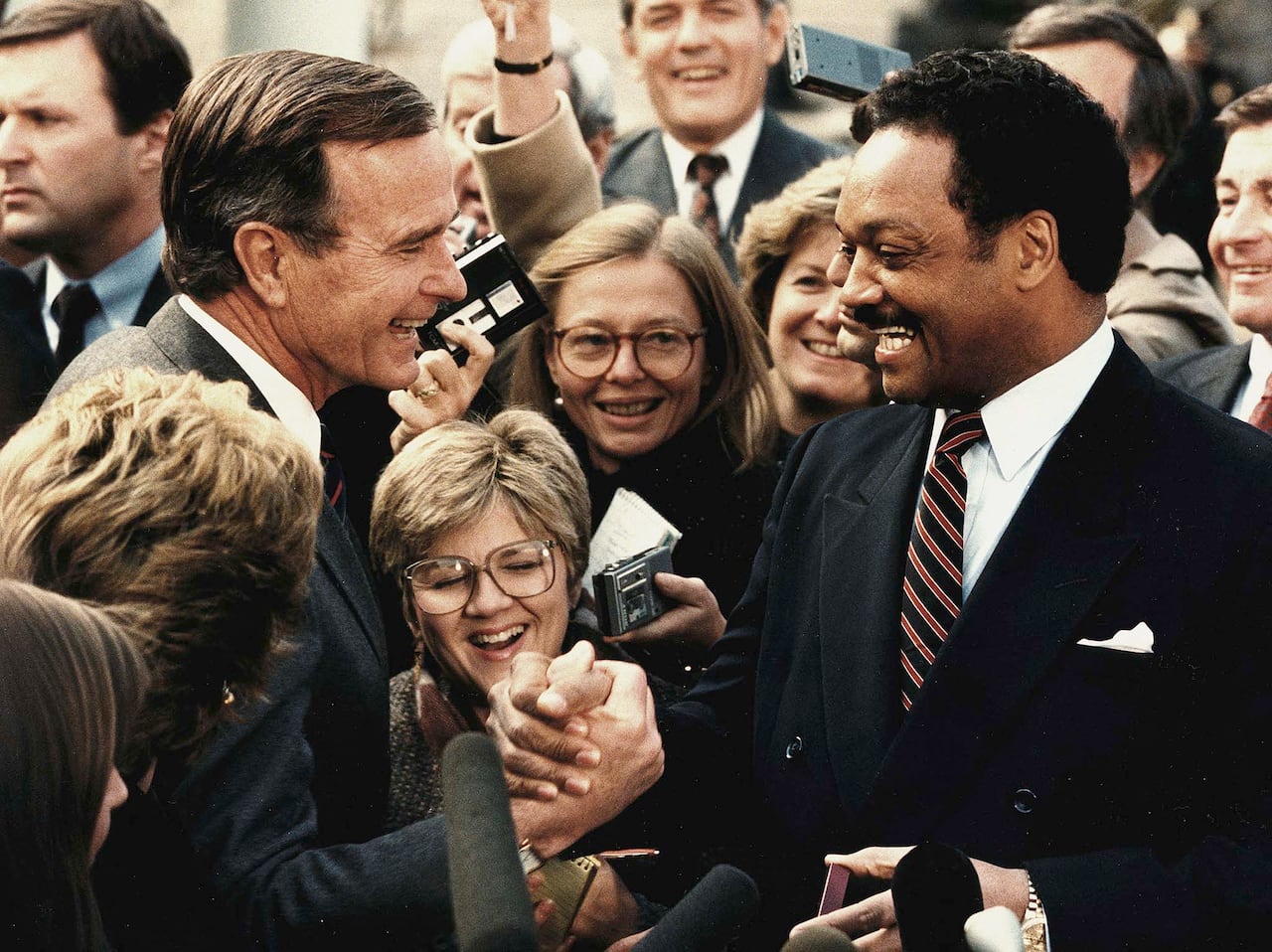 (ARCHIVOS) Esta foto de archivo muestra al expresidente electo George Bush (izq.) estrechando la mano del reverendo Jesse Jackson (der.), el 30 de noviembre de 1988, tras un almuerzo en la Casa Blanca, en Washington, D.C. El veterano activista estadounidense por los derechos civiles, el reverendo Jesse Jackson, falleció el 17 de febrero de 2026, según informó su familia en un comunicado. Tenía 84 años. (Foto de JEROME DELAY / AFP)