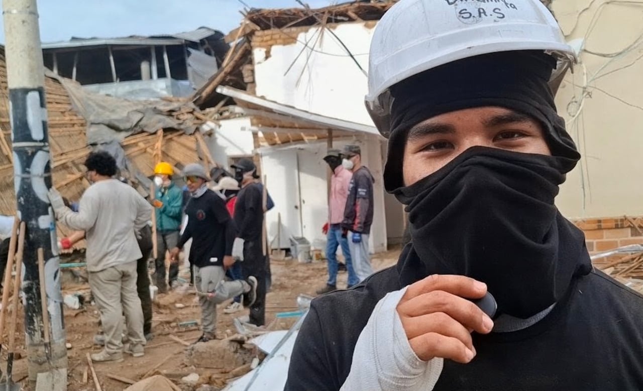 Un joven con casco y tapabocas se abre paso entre los escombros de una vivienda afectada por el sismo en Roldanillo.
