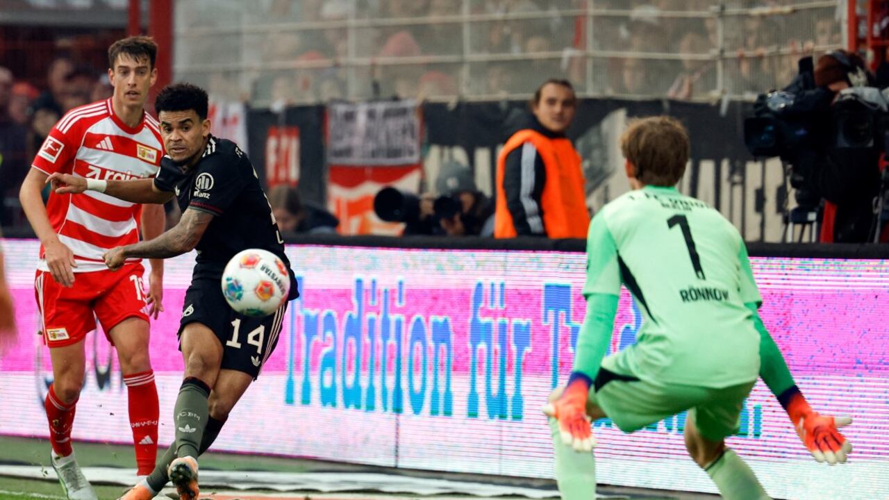 El delantero colombiano del Bayern Munich #14 Luis Díaz (C) anota el primer gol de su equipo ante el portero danés del Union Berlin #01 Frederik Ronnow.