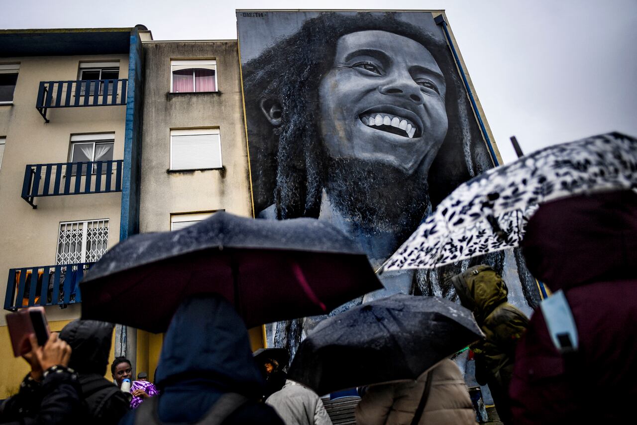 (FILES) In this file photo taken on November 17, 2019 Visitors watch a mural by Portuguese artist Odeith depicting Jamaican singer Bob Marley during a guided visit to Quinta do Mocho neighbourhood in Sacavem, outskirts of Lisbon. - It's been four decades since Bob Marley's death, a period longer than the reggae icon's brief but potent life that skin cancer ended when he was 36.