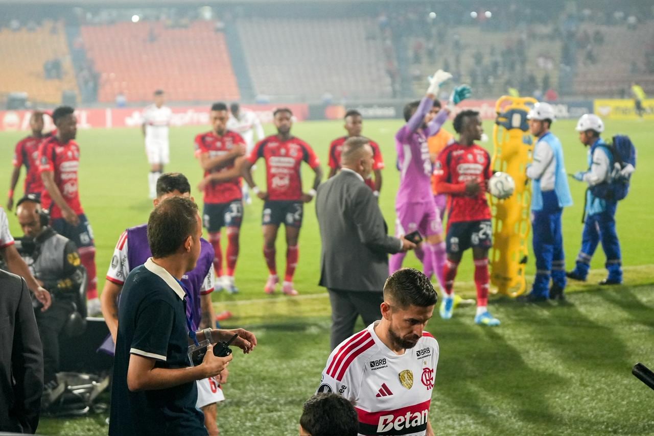 Jugadores del Independiente Medellín intentan calmar a los aficionados para reanudar el compromiso de Copa Libertadores contra Flamengo.
