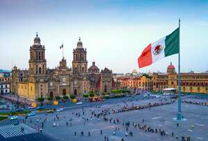 La bandera mexicana ondea sobre el Zócalo, la plaza principal de la Ciudad de México. La Catedral Metropolitana está frente a la plaza, también conocida como Plaza de la Constitución.