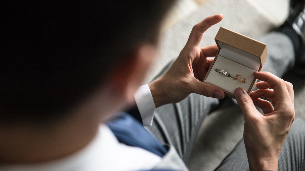 Novio sostiene anillos matrimoniales
