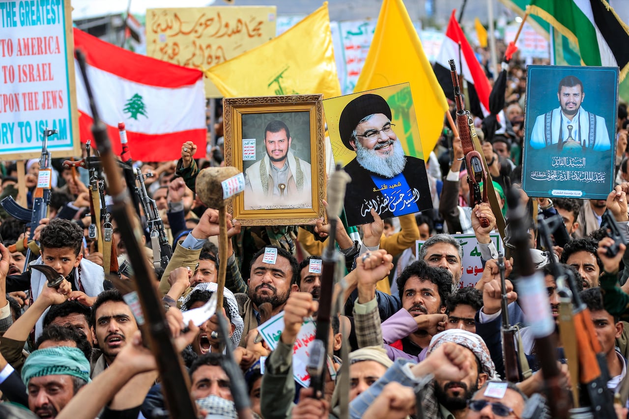 Supporters of the Iran-backed Houthi movement hold up the Lebanese flag (L), the yellow Lebanese Hezbollah party flag and a portrait of its slain leader Hassan Nasrallah (C-R) as they rally in solidarity with Iran and Lebanon in the Yemeni capital Sanaa on April 17, 2026. The Middle East war has created an "unprecedented shock" for the region's economies with no guarantee of a quick recovery, a senior International Monetary Fund official has told AFP. Five of the Gulf's eight oil- and gas-producing countries face a contraction this year, the IMF said in a regional report published on April 16. (Photo by Mohammed HUWAIS / AFP)