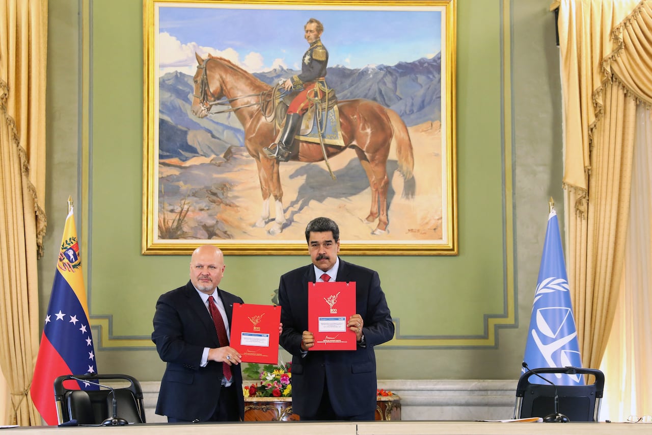 Foto del folleto publicado por la oficina de prensa del palacio presidencial de Miraflores que muestra al presidente de Venezuela, Nicolás Maduro (derecha) mientras muestra documentos con el Fiscal de la Corte Penal Internacional (CPI), Karim Khan, (izquierda) en el palacio presidencial de Miraflores en Caracas el 3 de noviembre. 2021. - Khan llegó el domingo a Venezuela como parte de una gira de 10 días por América Latina. (Foto Presidencia Venezolana / AFP) / RESTRINGIDO A USO EDITORIAL - CRÉDITO OBLIGATORIO - FOTO AFP / PRESIDENCIA VENEZOLANA - SIN MAFRKETING - SIN CAMPAÑAS PUBLICITARIAS - DISTRIBUIDO COMO SERVICIO A CLIENTES