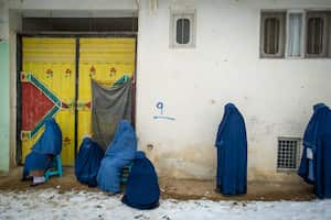 Mujeres afganas con burkas hacen fila, mientras el Programa Mundial de Alimentos (PMA) de las Naciones Unidas distribuye una ración alimentaria mensual crítica, con alimentos suministrados en gran parte por la Agencia de los Estados Unidos para el Desarrollo Internacional (USAID), a 400 familias al sur de Kabul en Pul-e Alam, Afganistán, el 17 de enero de 2022. Esta entrega de alimentos a la provincia de Logar se produce cuando la ONU advierte que 23 millones de afganos, más de la mitad de la población, están al borde de la hambruna, tras una sequía severa y a medida que el invierno se profundiza, mientras que Estados Unidos y el Banco Mundial solo han liberado parcialmente los fondos congelados cuando los talibanes tomaron el control de Afganistán en agosto de 2021. La ONU ha hecho un llamamiento de emergencia para recaudar 5.500 millones de dólares para alimentar a los hambrientos y evitar un mayor colapso económico. (Foto de Scott Peterson/Getty Images)