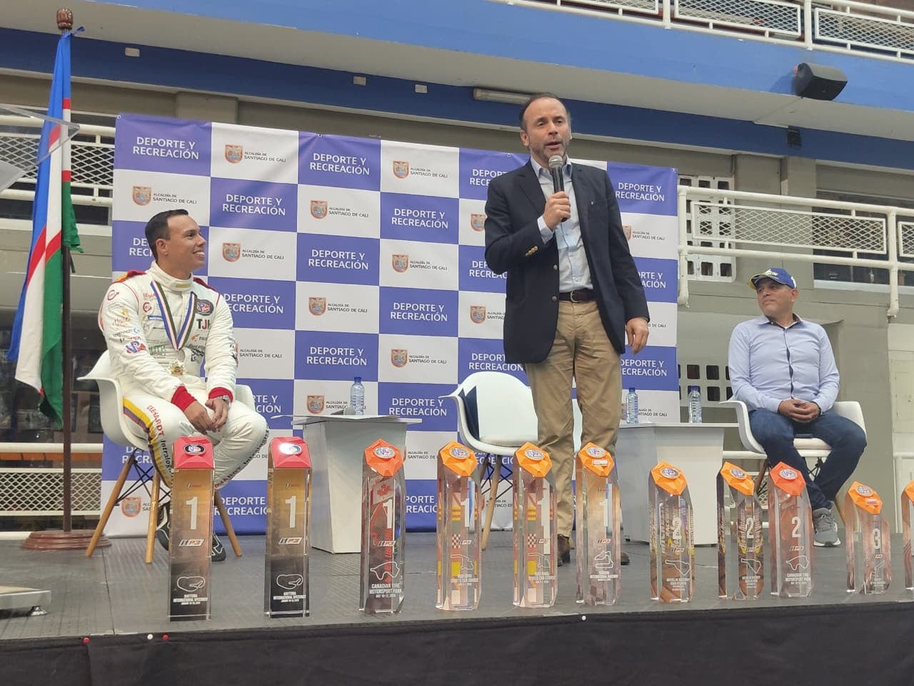 Óscar Tunjo (izq.) escucha las palabras de Alejandro Eder (centro), Alcalde de Cali, en su homenaje por el título en el IMSA VP Racing SportsCar Challenge.