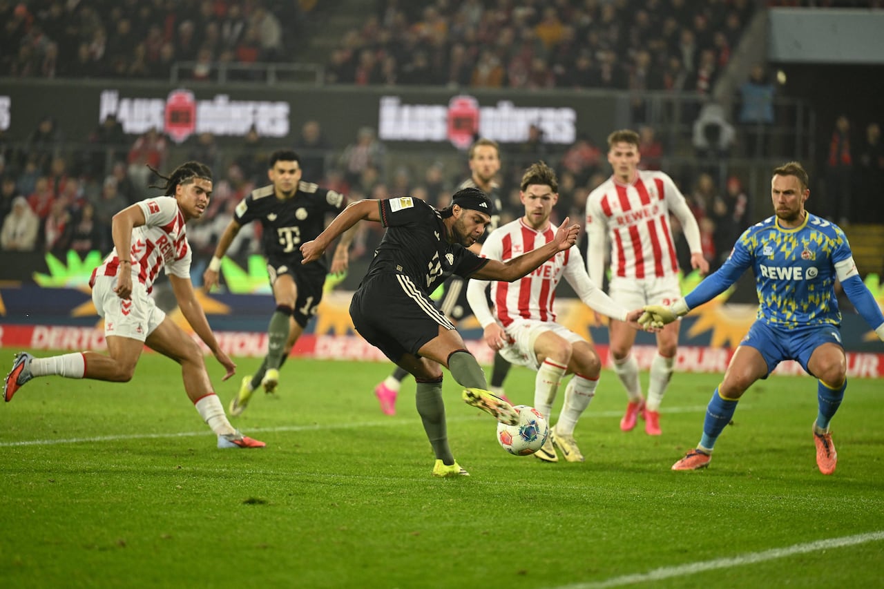 El delantero alemán #07 del Bayern Múnich, Serge Gnabry (C), marca el gol del 1-1 ante el portero alemán #01 del FC Colonia, Marvin Schwaebe (D), durante el partido de la Bundesliga alemana entre el FC Colonia y el FC Bayern Múnich en Colonia, Alemania, el 14 de enero de 2026. (Foto de INA FASSBENDER / AFP)