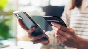 Mano de mujer sosteniendo tarjetas de crédito y usando un teléfono inteligente para comprar en línea con pago en banca por Internet.