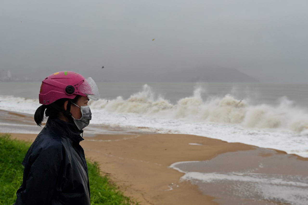 A woman watches waves crash onto Quy Nhon beach ahead of the arrival of Typhoon Kalmaegi in Gia Lai province in central Vietnam on November 6, 2025. The typhoon is forecast to make landfall in central Vietnam late on November 6, bringing waves as high as eight metres (26 feet) and powerful storm surges, according to the national weather bureau. (Photo by NHAC NGUYEN / AFP)