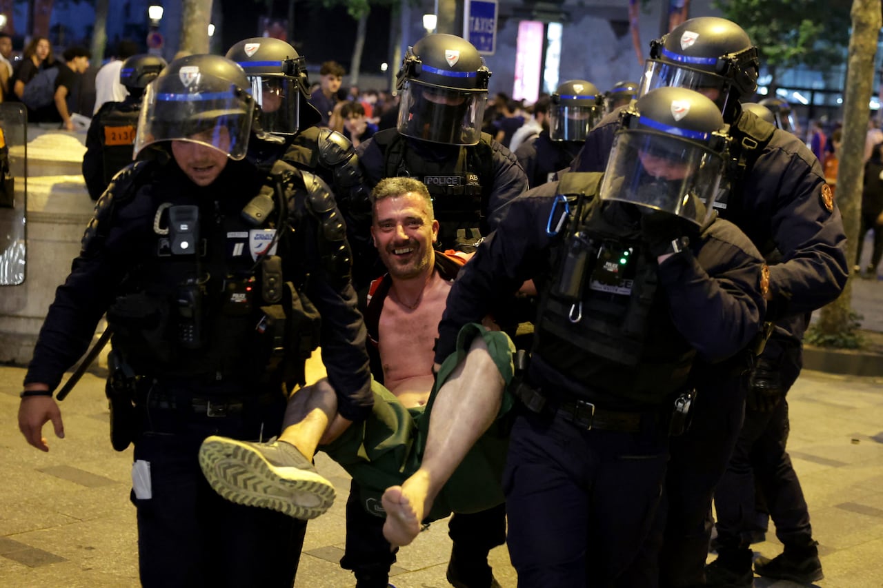 Agentes del Cuerpo Republicano de Seguridad de Francia (CRS - Compagnies Republicaines de Securité) detienen a un hincha del PSG durante las celebraciones tras la victoria de su equipo en la final de la Liga de Campeones de la UEFA entre el Paris Saint-Germain (PSG) y el Arsenal FC, disputada en Budapest, en la avenida de los Campos Elíseos de París el 30 de mayo de 2026. (Foto de ROMEO BOETZLE / AFP)