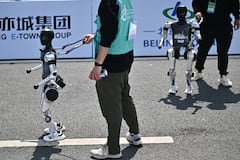 Se ve a robots y sus ingenieros tras cruzar la meta en la media maratón de robots humanoides celebrada en Pekín el 19 de abril de 2025. Decenas de robots humanoides recorrieron las calles de Pekín, uniéndose a miles de sus homólogos de carne y hueso en una media maratón pionera a nivel mundial que demostró el impulso de China por liderar la carrera global en tecnología de vanguardia. (Foto de Pedro PARDO / AFP)