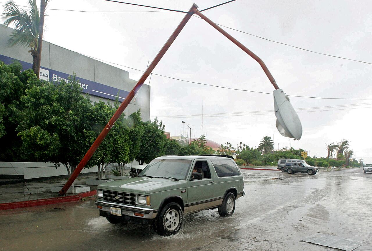Un vehiculo pasa debajo de un poste de luz a punto de caer luego del paso del Huracan John en La Paz, Baja California.
