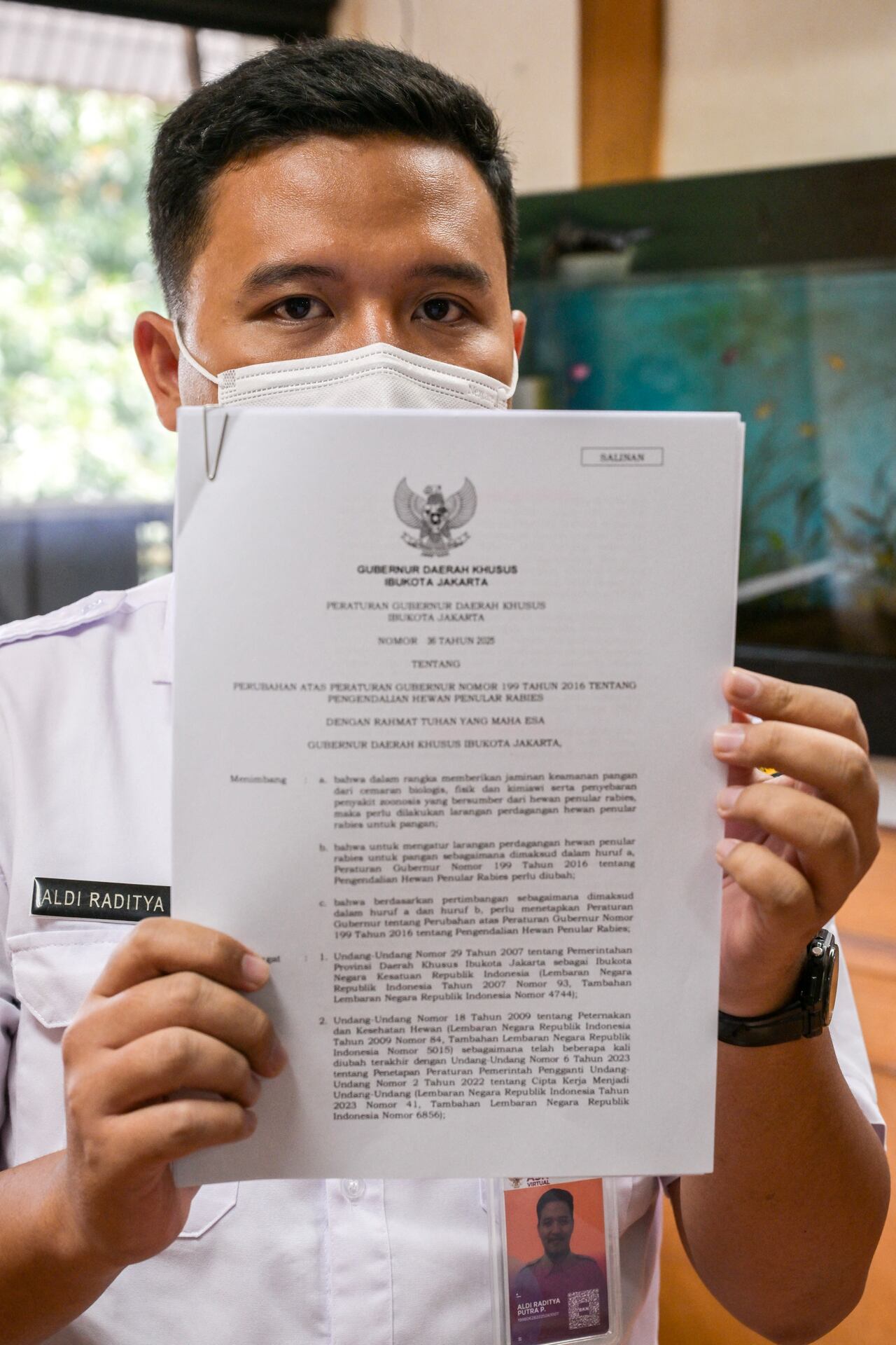 Un funcionario de la agencia de resiliencia alimentaria, marítima y agrícola de Yakarta (DKPKP) muestra una copia del reglamento del gobernador de Yakarta sobre la prohibición del comercio y consumo de carne de perro en su oficina de Yakarta el 26 de noviembre de 2025.