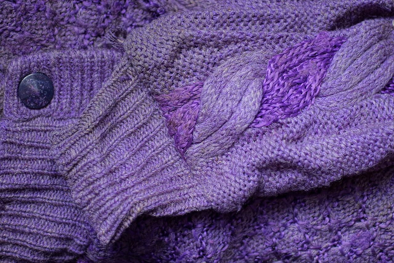 fabric texture of lilac wool knitted sweater with dirty old sleeve and button