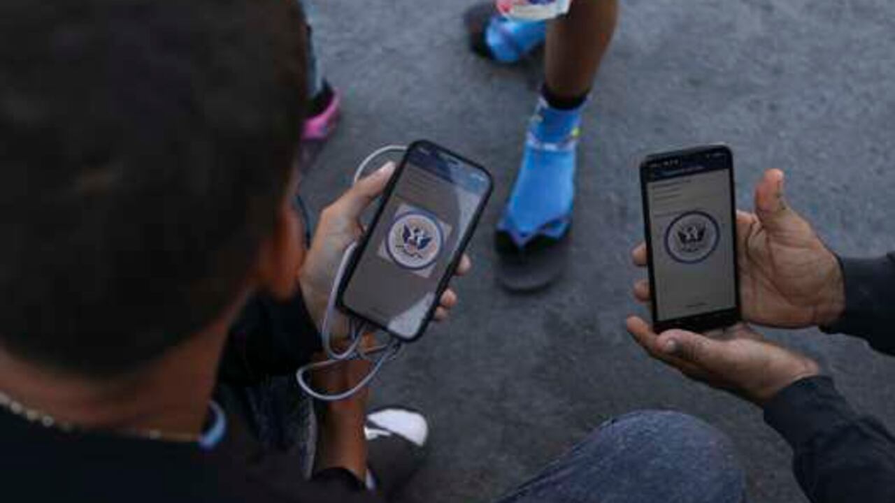Migrantes venezolanos navegan por la aplicación móvil CBP One en busca de una cita para ingresar a Estados Unidos fuera de la estancia temporal del Instituto Nacional de Migración (INM) en Ciudad Juárez, estado de Chihuahua, México