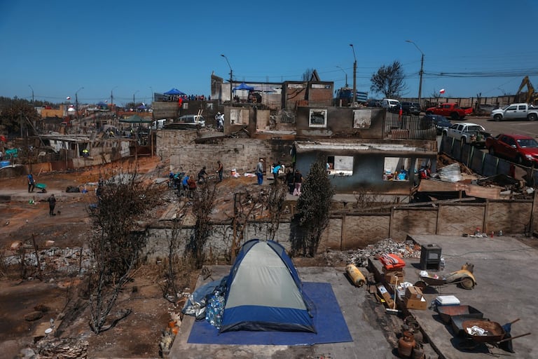 Residentes limpian escombros tras los devastadores incendios forestales que asolaron la zona el 3 de enero en Punta de Parra, cerca de Concepción, Chile, el 21 de enero de 2026. La policía del centro-sur de Chile arrestó a un hombre como sospechoso de iniciar uno de los recientes incendios forestales que causaron la muerte de 20 personas y arrasaron barrios enteros