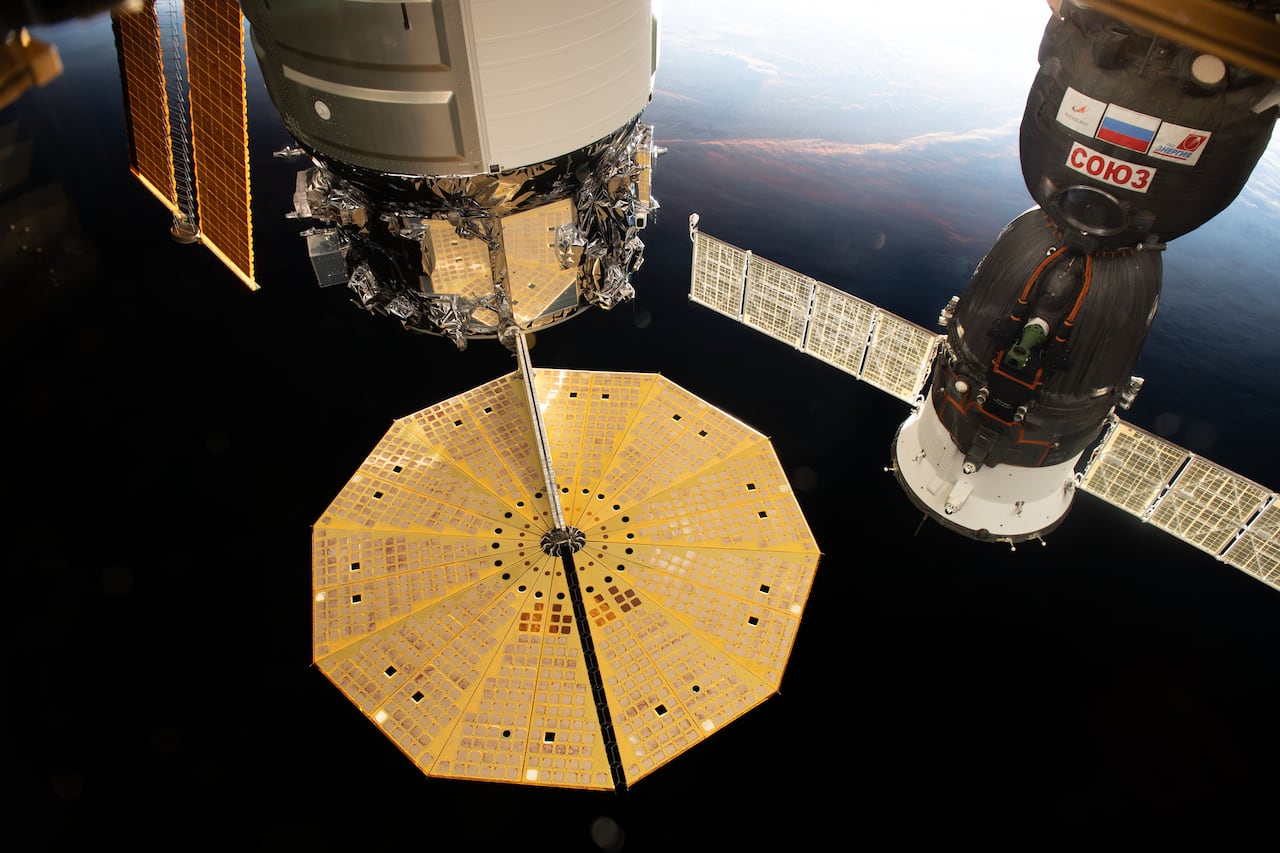 Oct. 18, 2020) --- Two spacecraft are pictured docked to the International Space Station as the complex flew into an orbital sunset above the Tasman Sea in between Australia and New Zealand. At left, with its prominent cymbal-shaped UltraFlex solar arrays is the Northrop Grumman's Cygnus resupply ship. To the right, is the Soyuz MS-17 crew ship that docked to the station on Oct. 14 carrying the Expedition 64 crew.