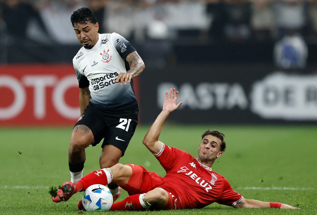 El defensa #21 de Corinthians, Matheus Bidu, y el delantero #10 de Huracán, Walter Mazzanti, luchan por el balón durante el partido de fútbol de la fase de grupos de la Copa Sudamericana.