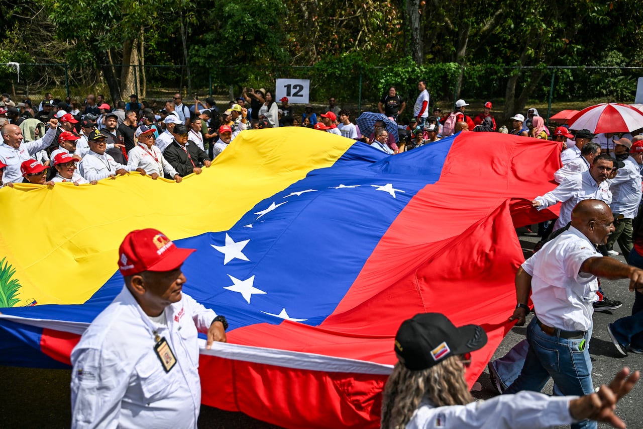 Demonstrators display a Venezuelan flag during a march calling for the lifting of all US sanctions in Caracas on April 30, 2026. Delcy Rodriguez announced on April 30 a 26% wage increase to the so-called "integral minimum income," raising it from 190 dollars to 240 dollars per month, the first adjustment since Nicolas Maduro's fall. (Photo by Juan BARRETO / AFP)