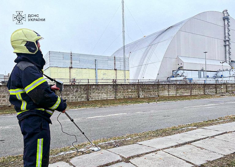 This handout photograph taken and released by Ukrainian Emergency Service on February 14, 2025 shows an employee working outside the New Safe Confinement (NSC), which protects the remains of reactor 4 of the former Chernobyl Nuclear Power Plant following a drone attack on its cover built to contain radiation. Ukraine's president said on February 14, that a Russian drone had struck overnight a cover built to contain radiation at the Chernobyl nuclear power plant. (Photo by Handout / UKRAINIAN EMERGENCY SERVICE / AFP) / RESTRICTED TO EDITORIAL USE - MANDATORY CREDIT "AFP PHOTO / UKRAINIAN EMERGENCY SERVICE " - NO MARKETING NO ADVERTISING CAMPAIGNS - DISTRIBUTED AS A SERVICE TO CLIENTS