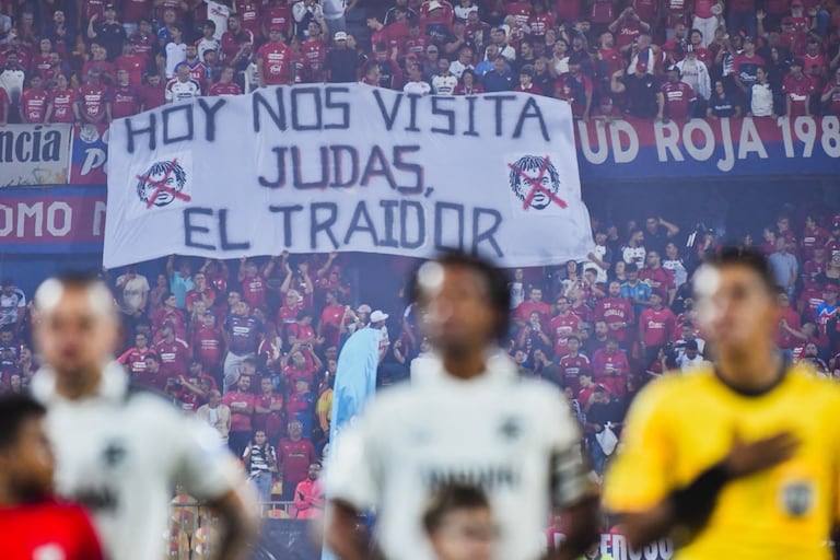 Juan Guillermo Cuadrado (centro) y atrás la pancarta o trapo de los hinchas del Independiente Medellín en su contra.