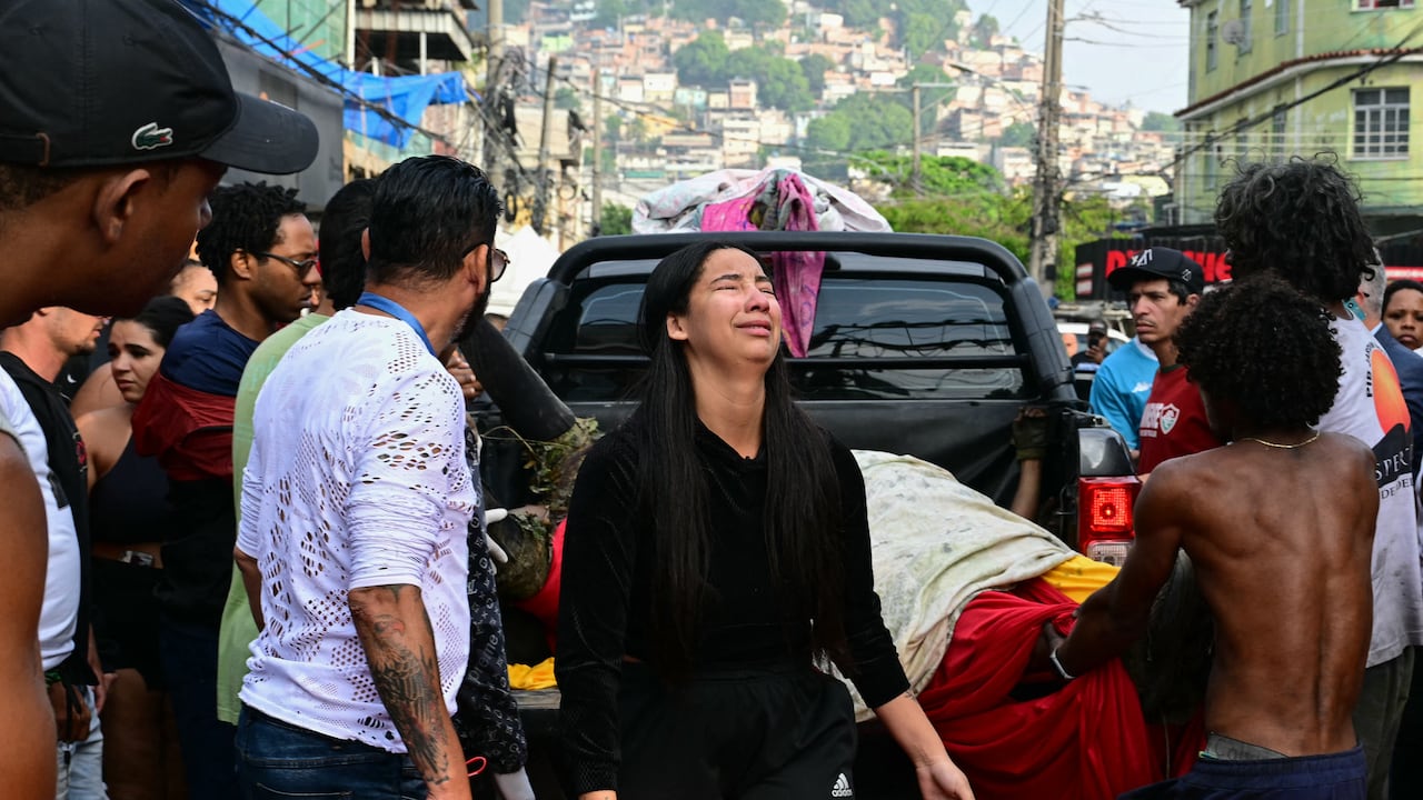 Una mujer llora mientras descargan cadáveres de una camioneta en la plaza São Lucas de la favela Vila Cruzeiro, en el complejo Penha de Río de Janeiro, Brasil, esto tras la Operación Contención. (Photo by Pablo PORCIUNCULA / AFP)