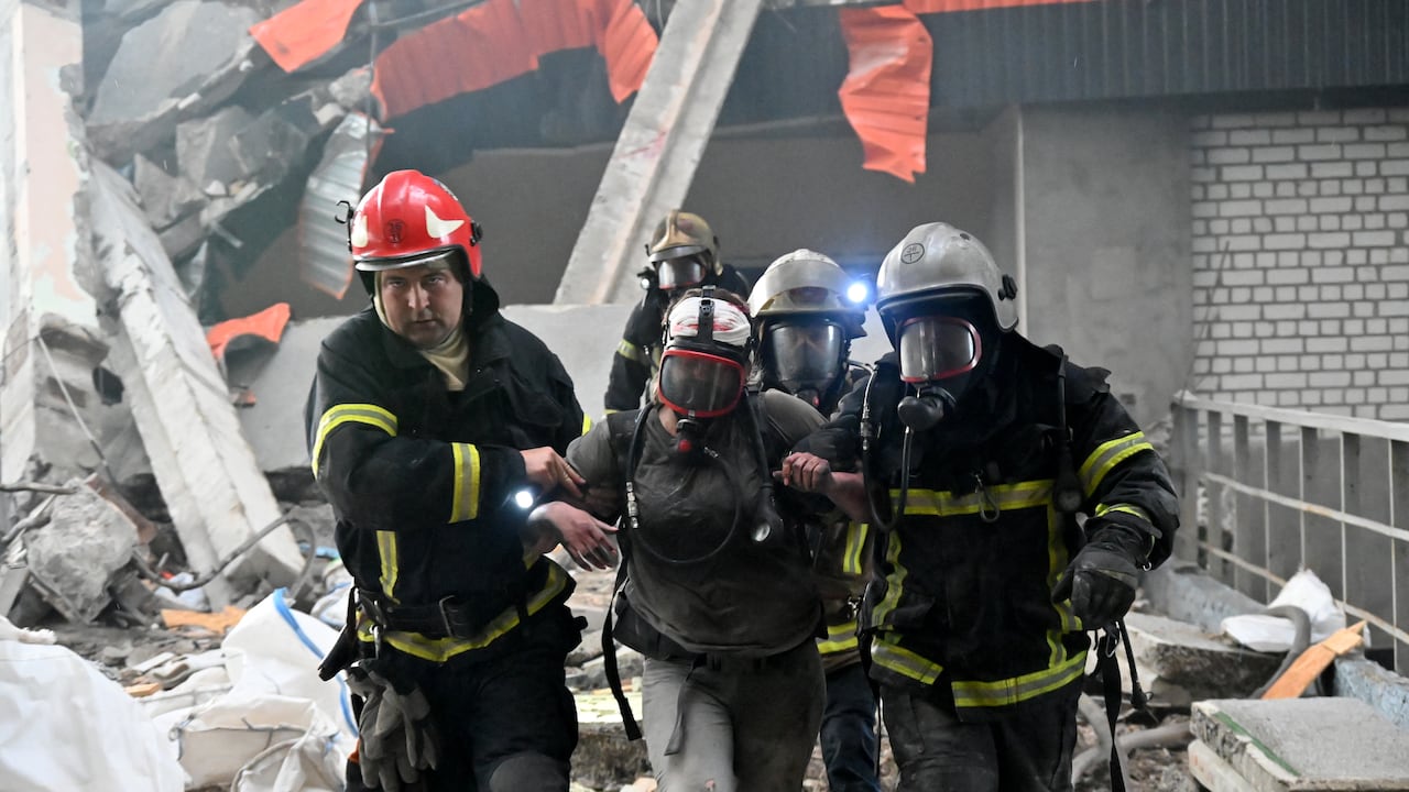 Los rescatistas ayudan a una persona herida a caminar entre los escombros de una planta civil.