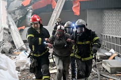 Los rescatistas ayudan a una persona herida a caminar entre los escombros de una planta civil.